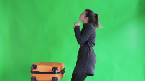 Молода жінка танцює з помаранчевою валізою на зеленому екрані — стокове відео