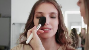 Profesyonel makyaj sanatçısı makyaj fırçası kullanarak modellerin yüzünü kızartıyor..