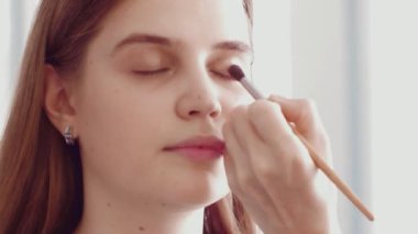 Profesyonel makyöz güzel bir beyaz modelin makyajını yapıyor..