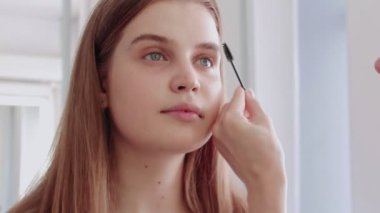 Profesyonel makyöz kirpiklerini kirpik fırçasıyla boyar..