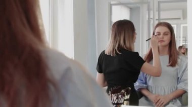 Profesyonel makyöz genç modelin makyajını yapıyor..