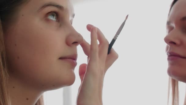 Makijażysta maluje pędzlem oczy do kobiety w salonie. zbliżenie wizażysty — Wideo stockowe