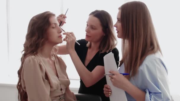 Adult professional teacher visagiste training her young student to become makeup artist at master class in beauty salon. — Stock Video