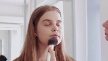 Profesyonel makyaj sanatçısı makyaj fırçası kullanarak yüzünü kızartır. Kozmetik konsepti. Yavaş çekim görüntüleri.