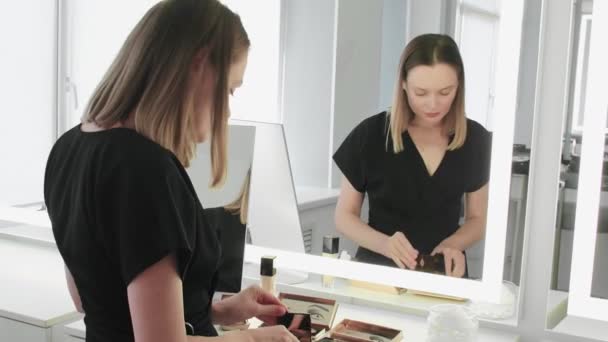 Young professional makeup artist waits for clients and prepares her work space — Stock Video