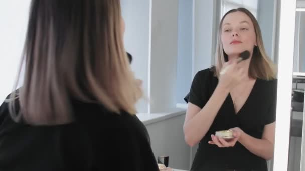 Frau macht Make-up. Junge Frau sorgt mit Make-up-Pinsel für Rouge im Gesicht. — Stockvideo