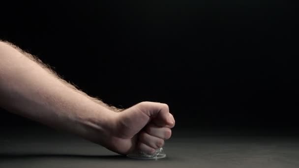 Крупный план мужского кулака давит пластиковую чашку на черном фоне — стоковое видео