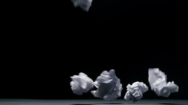 Смятая бумага падает на черном фоне в замедленной съемке — стоковое видео