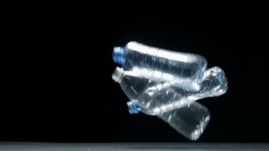 Plastik kirliliği. Plastik Şişe siyah arkaplana düşüyor