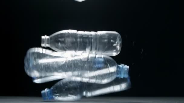 プラスチック汚染だ。黒の背景に落ちてくるペットボトル — ストック動画