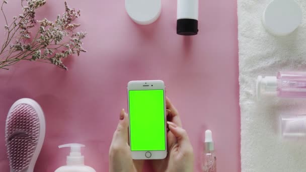 Kvinnan knackar på telefonen med grön skärm. Skönhet tema platt låg kreativ layout overhead med pro miljö. — Stockvideo