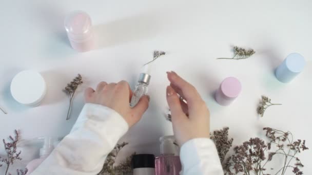 Woman applying face serum on her hands. Beauty theme flat lay creative layout overhead with pro environment. — Stock Video