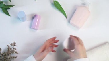 Kadın kremi, güzellik desenini düzleştirmek için açar. Beyaz arka planda profesyonel çevre ile birlikte yaratıcı bir düzen oluşturur.