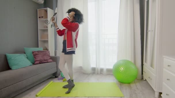 Nuori afrikkalainen amerikkalainen nainen hippi värikkäissä urheiluvaatteissa, joissa on kiharat afrokarvat, katsoo peiliin harjoittelun jälkeen. — kuvapankkivideo