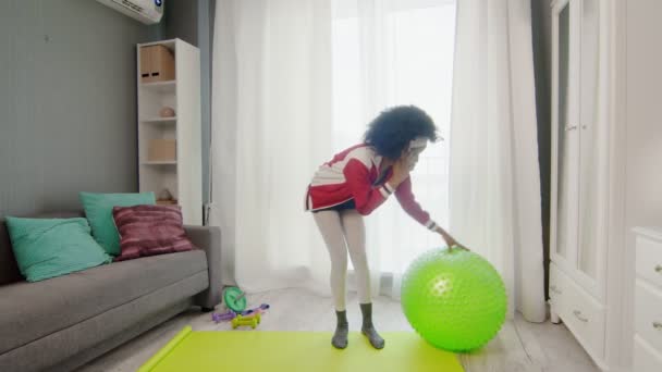 Joven mujer afroamericana hippy en ropa deportiva colorida con pelos afro rizados está hablando por teléfono en el descanso en el entrenamiento — Vídeo de stock