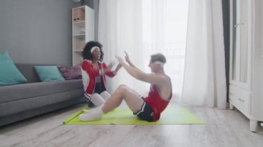 Kafkas erkek ve afro kadının evde iş yaptığı komik bir retro tarzı. Karın kasları çalıştıran komik bir adam. Evde eşiyle mekik çekiyor, spor yapıyor..