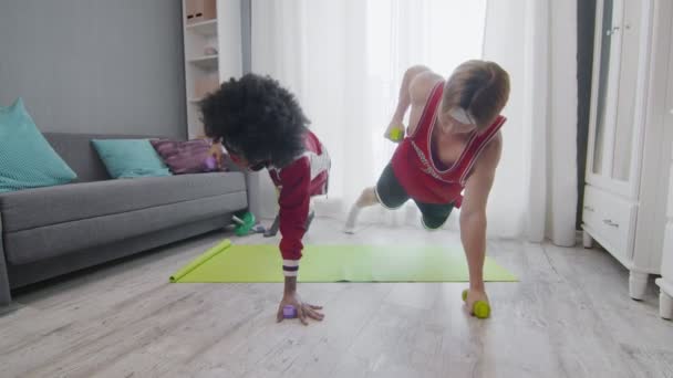 Çılgın genç çift evde dambıllarıyla egzersiz yapıyor. — Stok video