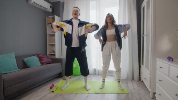 Pasangan muda bahagia yang sehat pria dan wanita bekerja di rumah. Mereka melakukan latihan peregangan — Stok Video
