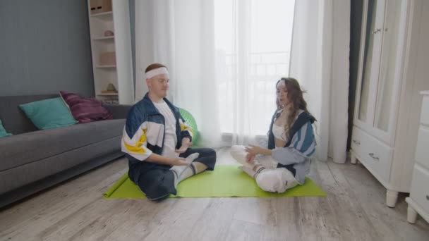 Keluarga muda fit duduk di lantai, bermeditasi bersama-sama, menjaga gaya hidup sehat — Stok Video