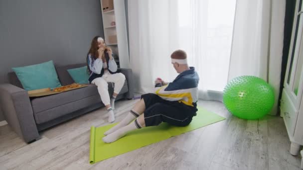 Rétro élégant jeune femme manger pizza tandis que son copain faire rotation exercice avec haltère — Video