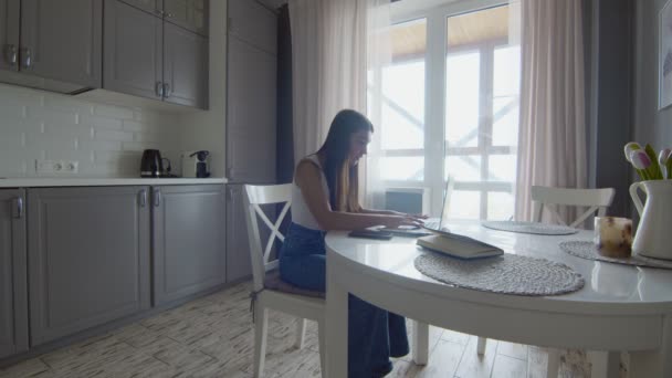 Молодая современная женщина разговаривает на мобильном ноутбуке на кухне интерьера. — стоковое видео