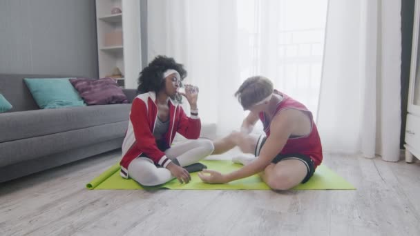 Funny retro style couple of Caucasian man and african american woman relaxes after hard work out — Stock Video