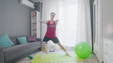 Retro stil genç adam evde aerobik egzersizi yapıyor.