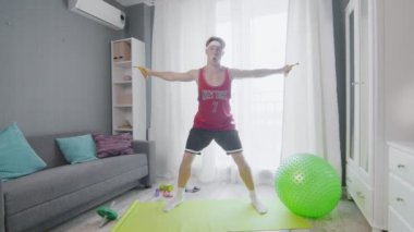 Komik görünüşlü adam evde muzla egzersiz yapıyor..