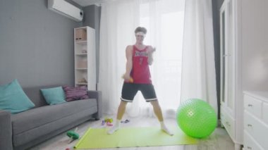 Komik görünüşlü adam evde muzlu pazılarla egzersiz yapıyor..