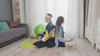 Genç, zemin üzerinde oturan sağlıklı bir aile, birlikte meditasyon yapıyorlar, sağlıklı bir yaşam sürüyorlar. Erkek arkadaşı meditasyon yaparken Wpman telefonu kullanıyor.