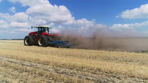Фермер на красном тракторе пашет пыльную засушливую почву. За фермерским вагоном следуют голодные птицы. Агробизнес весной — стоковое видео