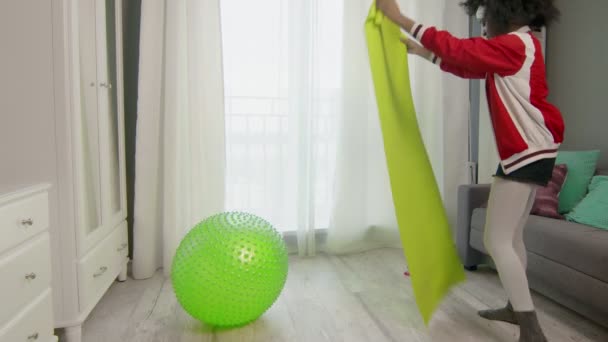 Young african american woman hippy in colourful sportswear with curly afro hairs is preparing to do work out at home. Woman spreads the mat for training — Stock Video