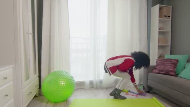 Young african american woman hippy in colourful sportswear with curly afro hairs is gets ready do work out at home — Stock Video