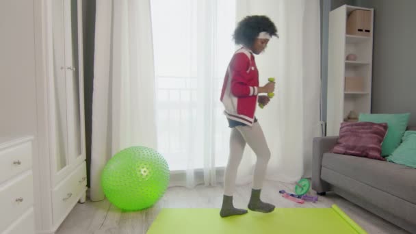 Young african american woman hippy in colourful sportswear with curly afro hairs is lifting green dumbels — Stock Video