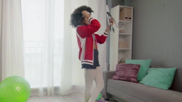 Young african american woman hippy in colourful sportswear with curly afro hairs is looking at the mirror after training — Stock Footage Young african american woman hippy in colourful sportswear with curly afro hairs is looking at the mirror after training Royalty Free Stock Footage