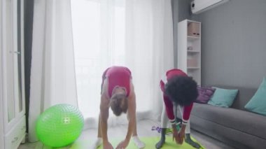 Neşeli Kafkasyalı adam ve Afrikalı Amerikalı kadın eski moda modeller evde antrenman yapıyor.