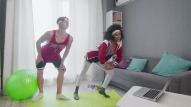 Kafkas erkek ve afro kadın dizüstü bilgisayarda spor yapıyor ve spor videoları seyrediyor.