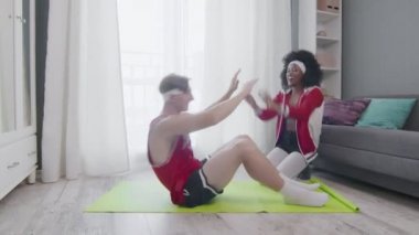 Kafkas erkek ve afro kadının evde iş yaptığı komik bir retro tarzı. Karın kasları çalıştıran komik bir adam. Evde eşiyle mekik çekiyor, spor yapıyor..