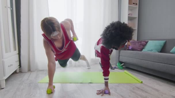 Crazy retro young couple doing exercises with dumbbells at home — Stock Video