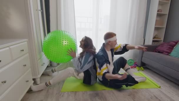 Pasangan muda yang sehat pria dan wanita bekerja di rumah. Mereka melakukan latihan dengan bola kebugaran — Stok Video