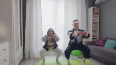 Mutlu, genç ve sağlıklı çift evde çalışıyor. Dambıllarla çömeliyorlar.