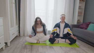 Genç, zemin üzerinde oturan sağlıklı bir aile, birlikte meditasyon yapıyorlar, sağlıklı bir yaşam sürüyorlar. Kadın erkek arkadaşının fotoğrafını çekiyor.