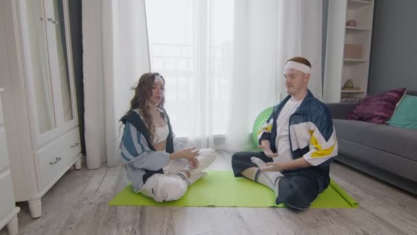 Молода сім'я сидить на підлозі, роздумуючи разом, зберігаючи здоровий спосіб життя — стокове відео