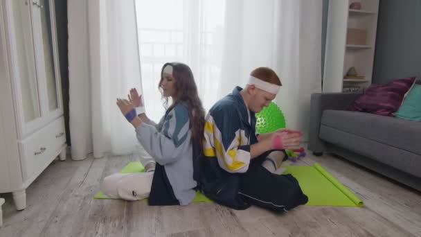 Pendatang baru pria dan wanita konyol dalam olahraga dengan pakaian olahraga berwarna-warni melakukan latihan tangan dengan band elastis — Stok Video