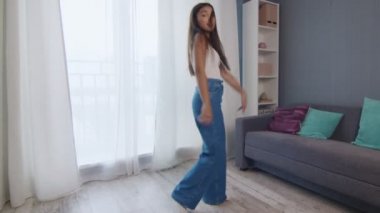 Mutlu bir kızın enerjik dansı. Oturma odasında dans eden ve müzik dinleyen güzel genç bir kadın..