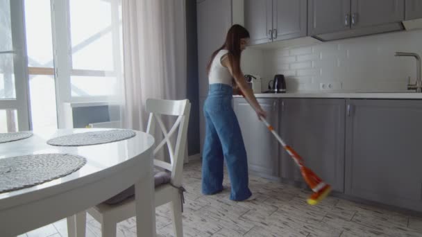 Joven hermosa mujer limpia el suelo con fregona en la cocina — Vídeos de Stock