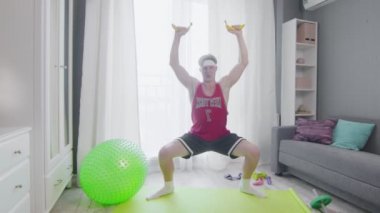 Komik görünüşlü adam evde muzla egzersiz yapıyor..