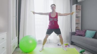 Komik görünüşlü adam evde muzla egzersiz yapıyor..