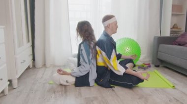 Genç, zemin üzerinde oturan sağlıklı bir aile, birlikte meditasyon yapıyorlar, sağlıklı bir yaşam sürüyorlar. Erkek arkadaşı meditasyon yaparken Wpman telefonu kullanıyor.