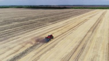 Traktör buğday ekmek için tarlayı sürüyor. Tarlada yeni ve güzel bir traktör arkasında güzel bir arka plan bırakır.